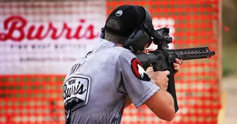 man shooting in front of orange mesh