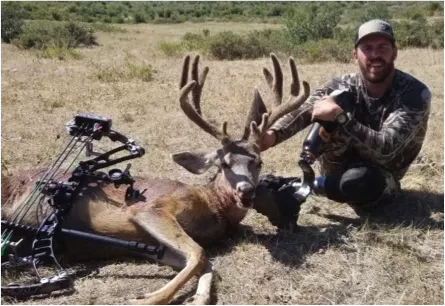 man kneeling with big game kill