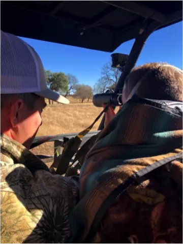 two men in vehicle using binoculars