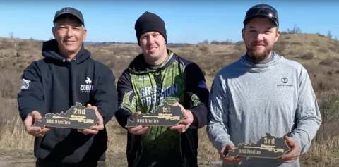 Three competition shooters holding up tropies
